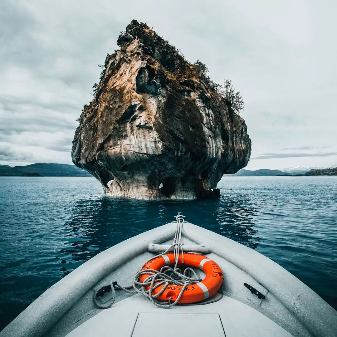 Proa de un bote con salvavidas acercándose a una formación de mármol en el lago General Carrera