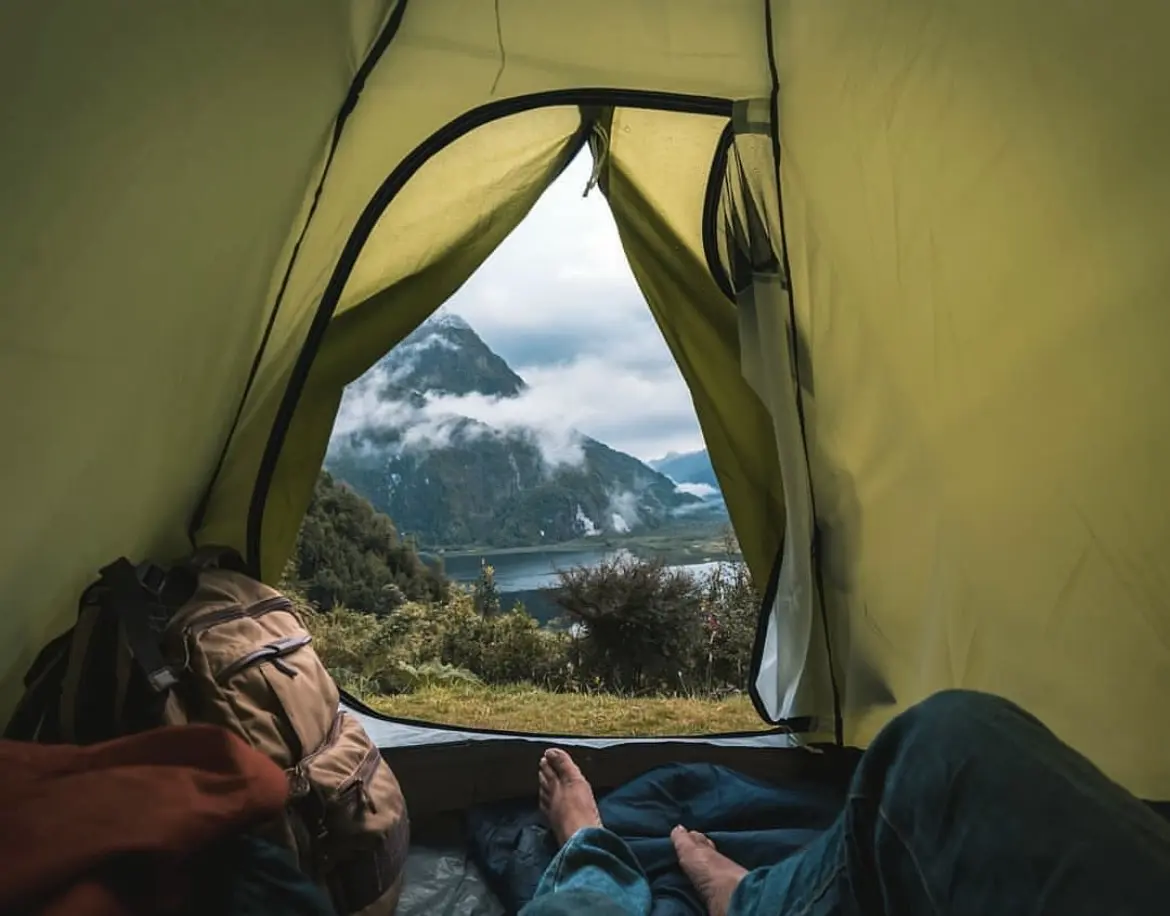 Vista desde el interior de una carpa hacia las montañas y el agua en un camping del Parque Pumalín
