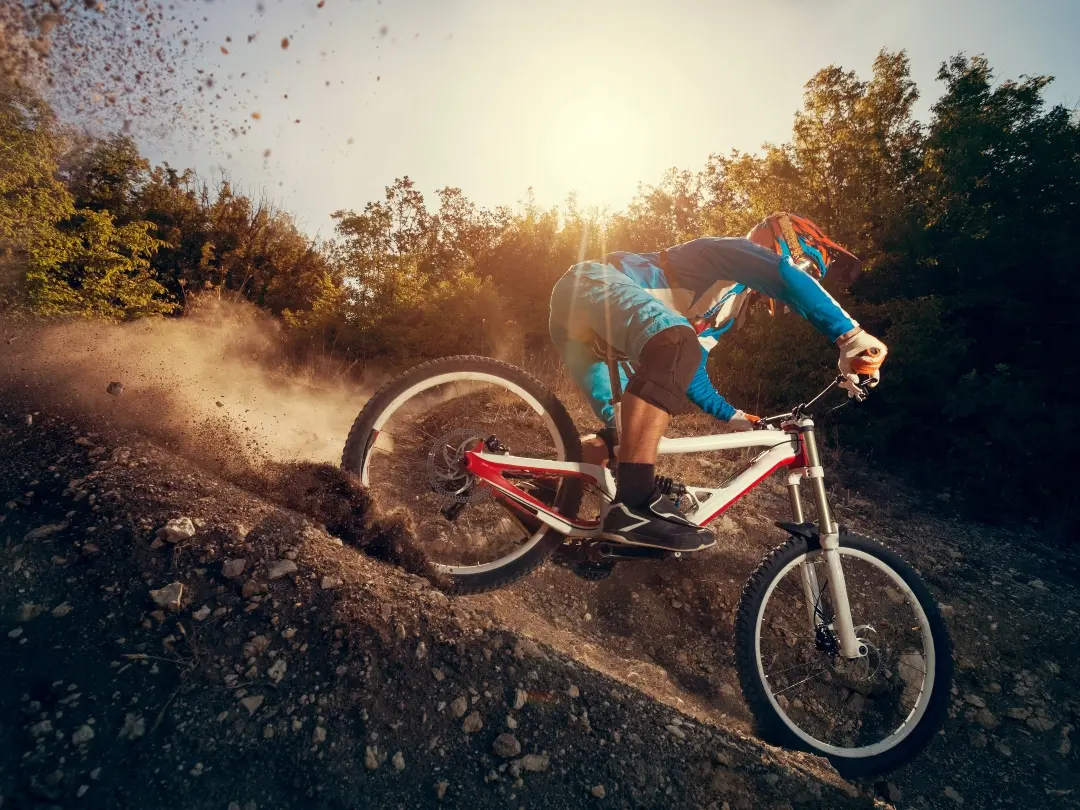 Ciclista de montaña bajando por un sendero de tierra al atardecer
