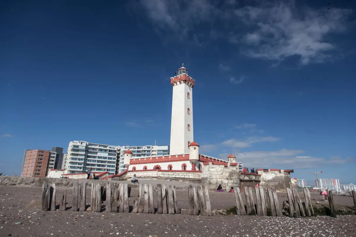 Faro Monumental de La Serena frente a la playa, con cielo azul y pilotes de madera en primer plano