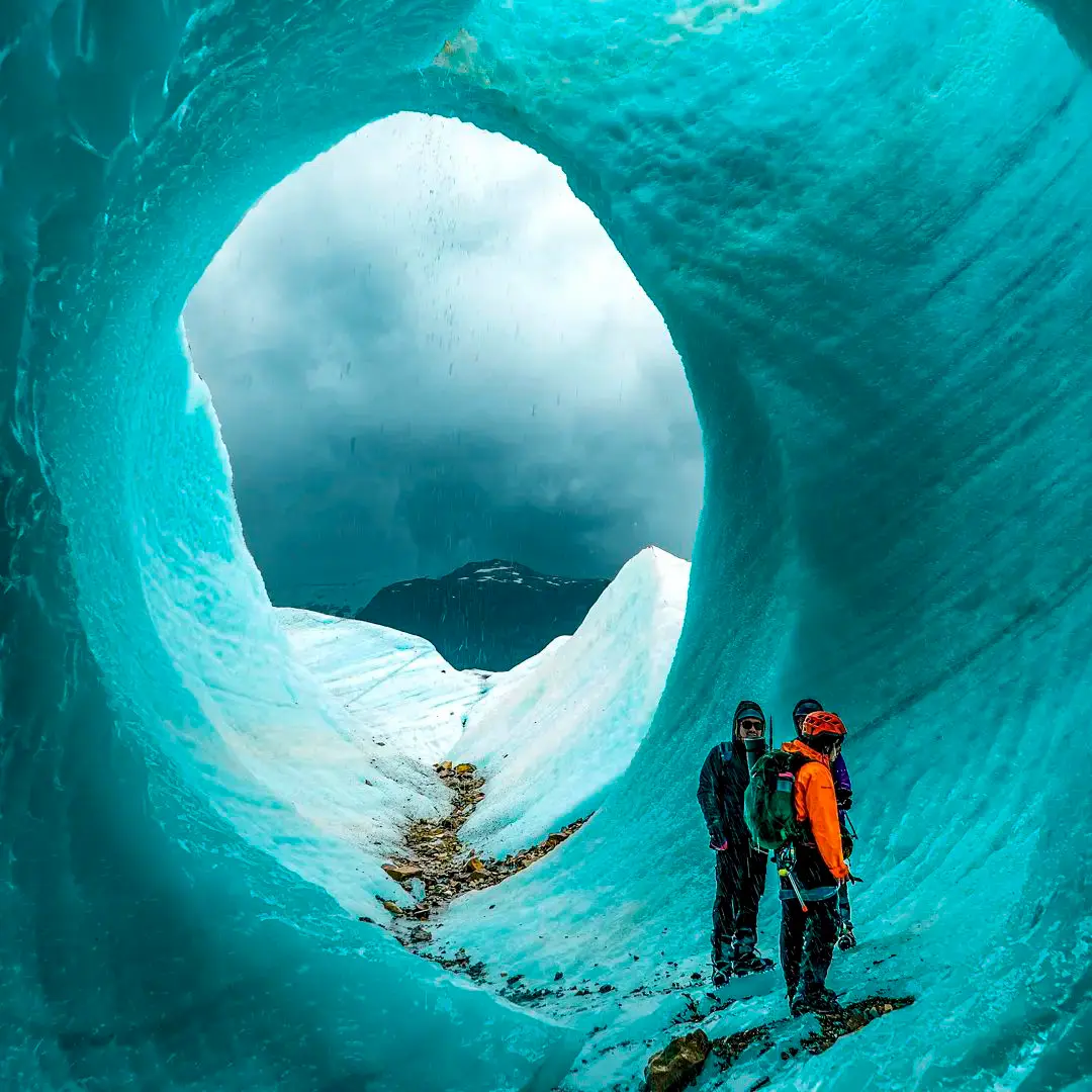 Dos personas dentro de un túnel de hielo azul en el glaciar Exploradores