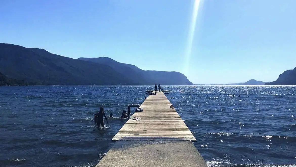 Muelle de madera que se adentra en el lago Cólico, con cerros boscosos al fondo