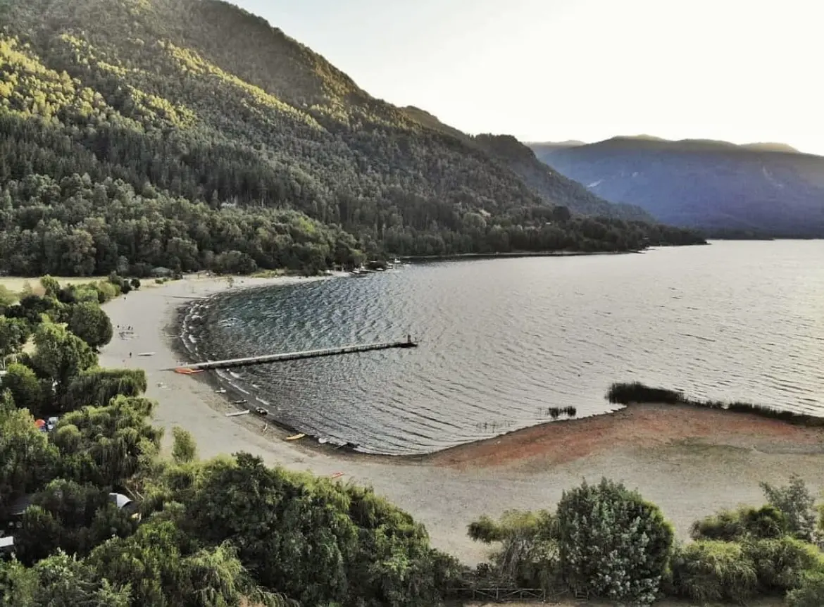 Playa de arena y piedras con un muelle de madera en la orilla del lago Cólico