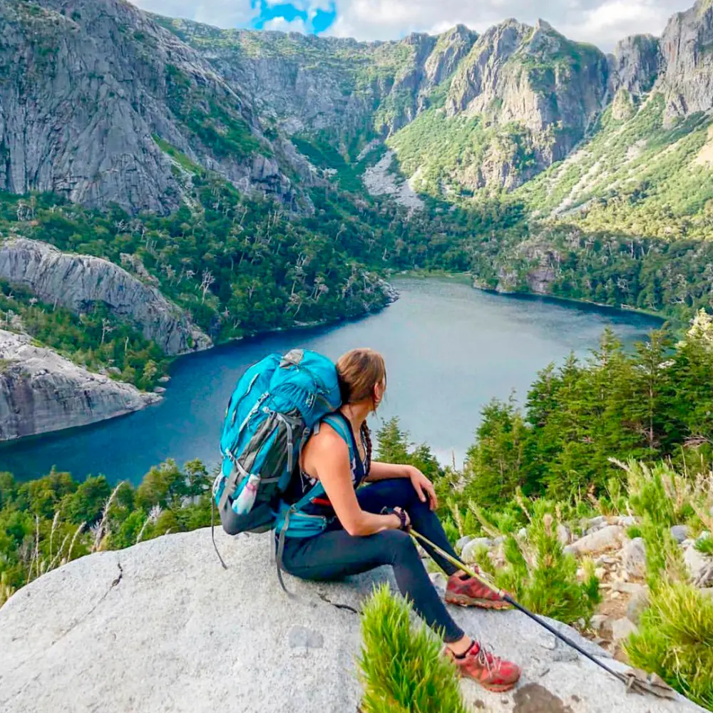 Excursionista mirando una laguna encajonada entre cerros en el Alto Biobío