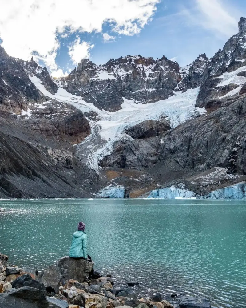 Excursionista frente a una laguna turquesa y un ventisquero en el sendero Las Horquetas