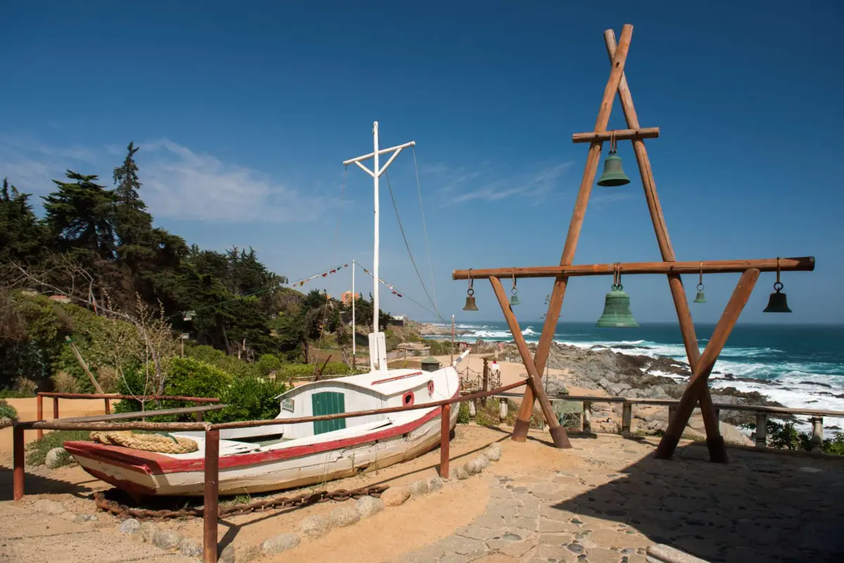 Bote varado y campanas de madera frente al mar en el Litoral de los Poetas