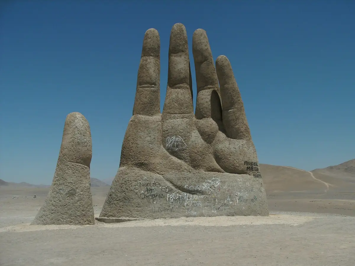 Mano del Desierto de día frente al cielo azul y el suelo arenoso