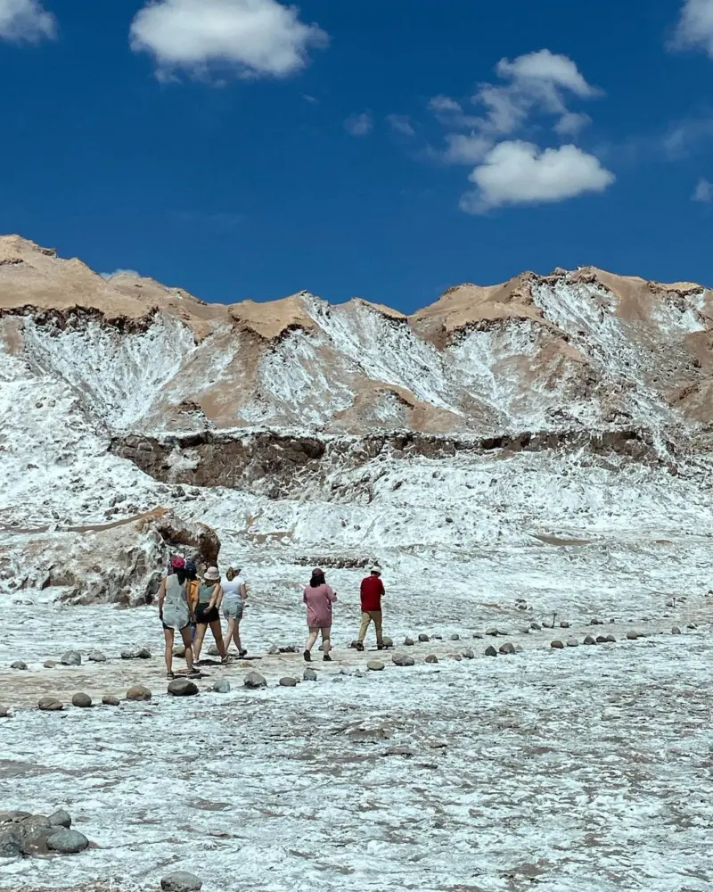 Grupo de visitantes caminando sobre formaciones de sal en el desierto de Atacama