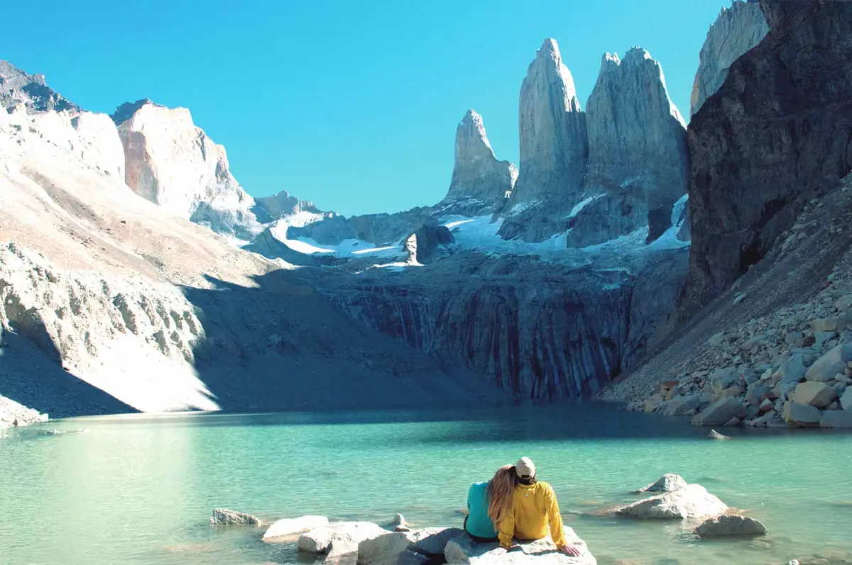 Torres del Paine y laguna turquesa con dos excursionistas descansando