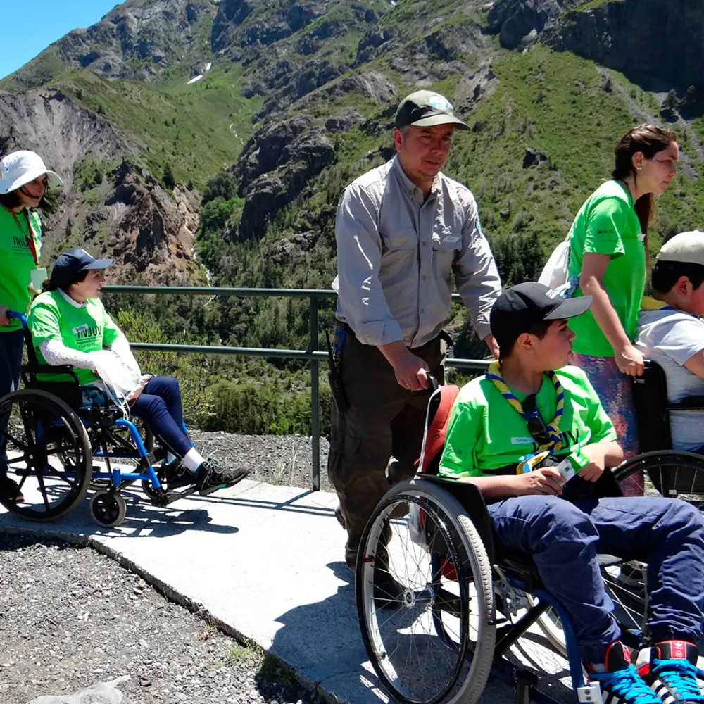 Visitantes con apoyo caminando por un mirador accesible en el Parque Nacional Laguna del Laja