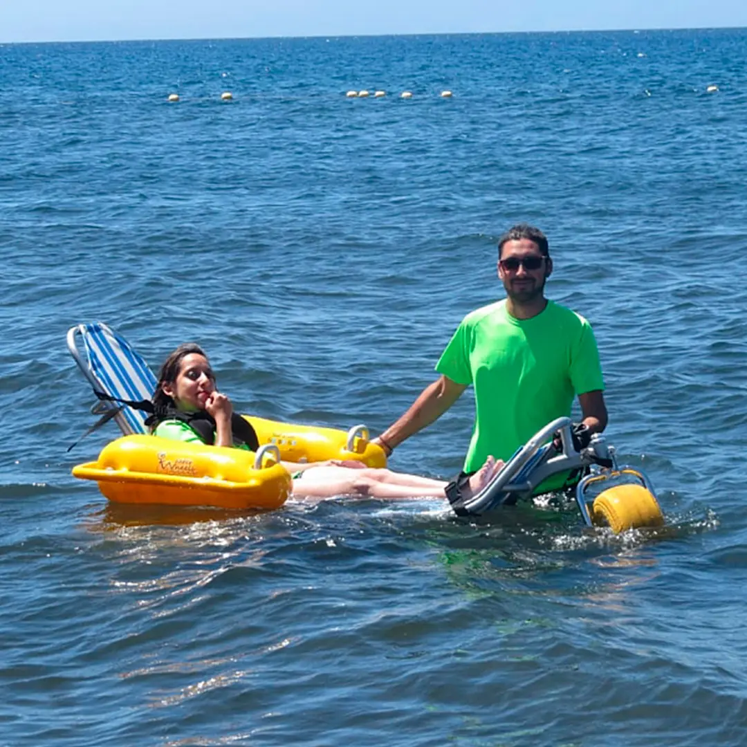 Monitor ayudando a una niña en una silla anfibia dentro del agua