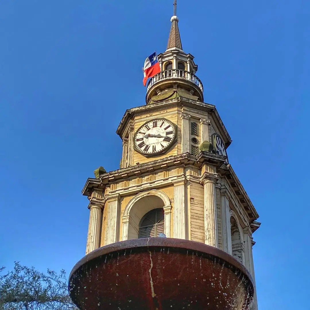 Torre con reloj de una iglesia patrimonial chilena bajo un cielo azul